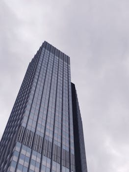 在德国美因河畔法兰克福，一座当代摩天大楼从下方被拍摄，天空阴沉