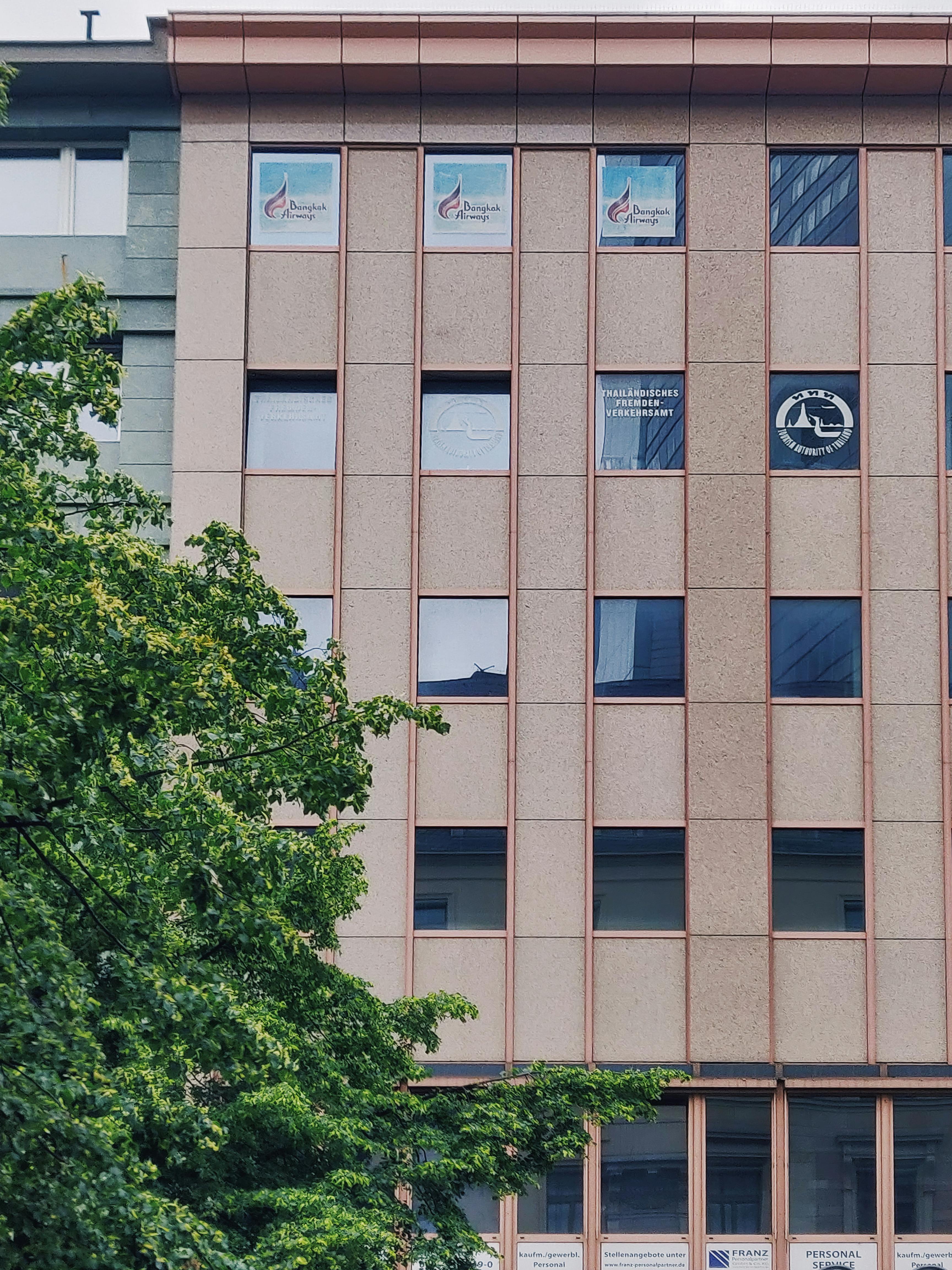 法兰克福一栋现代化办公楼的前视图，玻璃窗设计，周围环绕着绿色植物