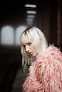 一位时尚女性身着粉色毛皮大衣，在变幻的灯光下摆出姿势，凸显出时尚与质感
