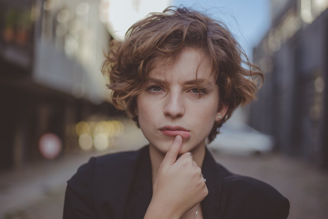 Free Selective Focus Portrait Photo of Woman Posing with Her Thumb Below Her Lip Stock Photo