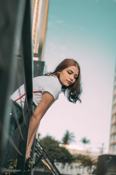 一名穿着休闲装的年轻女子靠在城市环境的阳台栏杆上