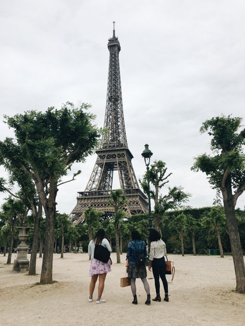 Free Three tourists admire the Eiffel Tower from a nearby park in Paris, perfect for travel and tourism themes. Stock Photo