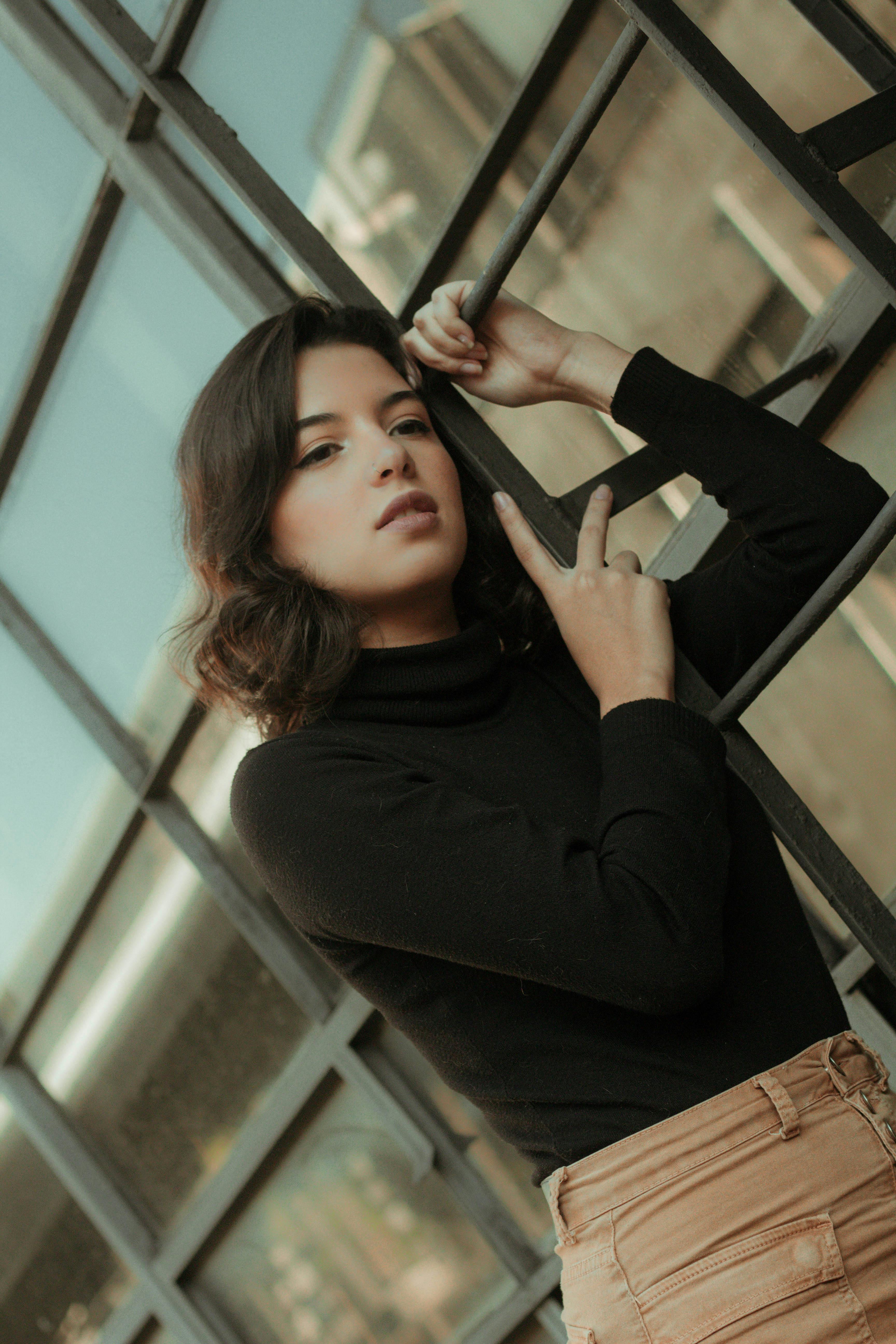 一位时尚的年轻女子在城市屋顶的梯子上，散发着沉思的气息