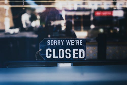 Close-Up Photo of Sorry We're Closed Sign on Glass Window