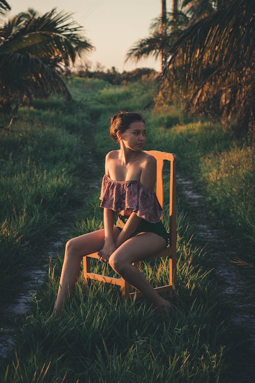 Foto Der Frau, Die Rohrbluse Beim Sitzen Auf Holzstuhl Trägt