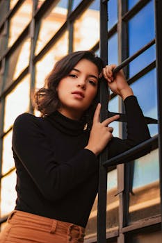 一位穿着休闲装的时尚女性倚在窗梯上，摆出反光的姿势