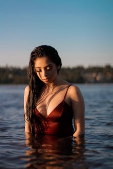 一名女子穿着泳衣站在水中，享受着宁静的日落