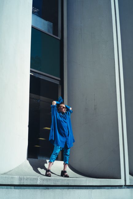 A stylish woman in blue poses against a contemporary building facade in Portland, showcasing urban fashion.