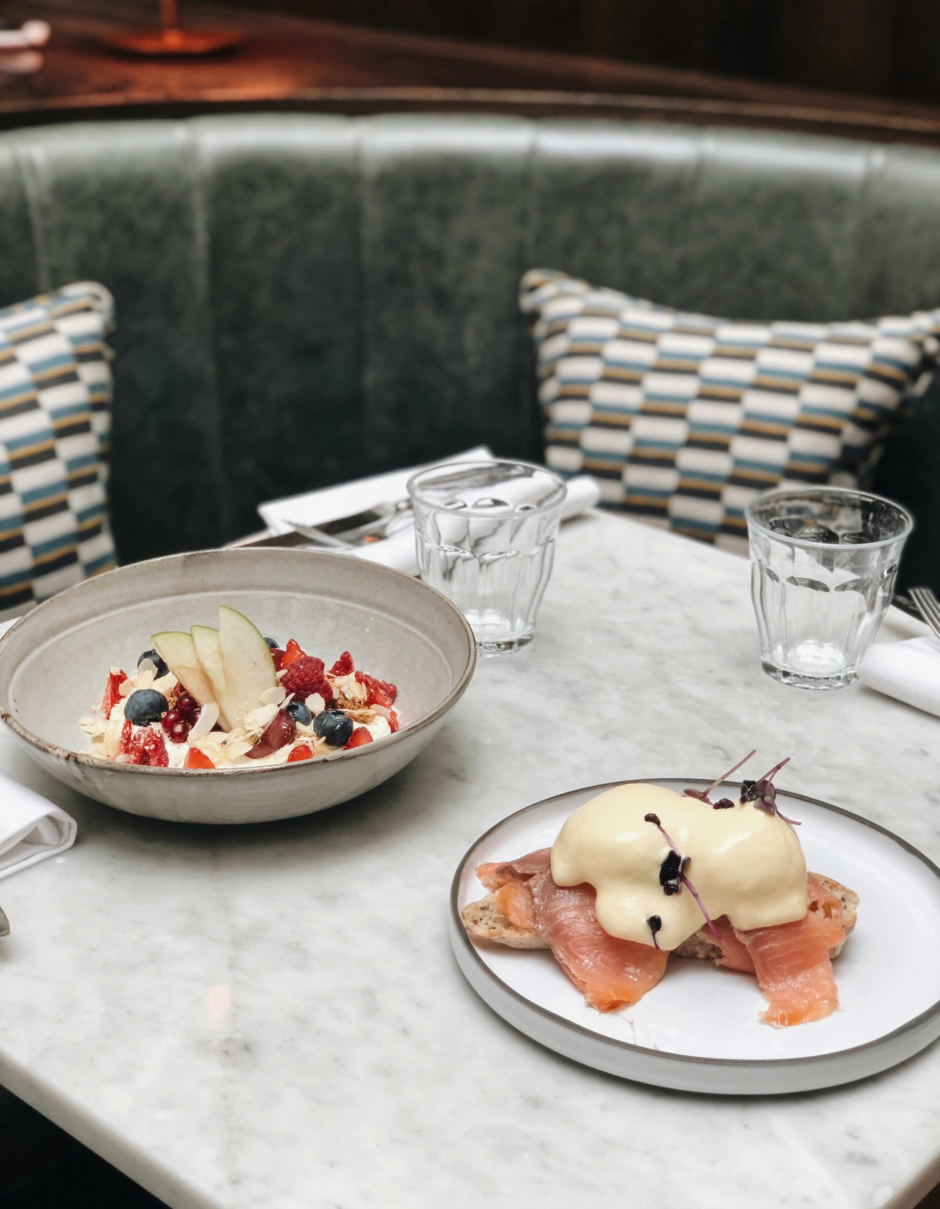 A gourmet breakfast featuring smoked salmon and fruit salad served elegantly on a marble table.