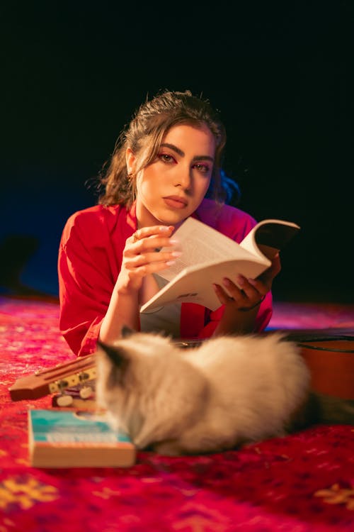 A woman reading a book while sitting on a carpet