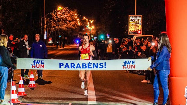 在夜间马拉松中，跑步者冲过终点线，庆祝胜利