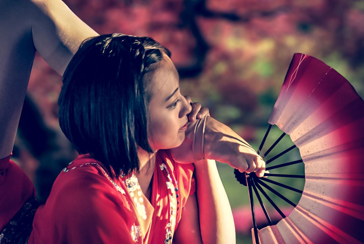 a woman in traditional attire gracefully poses with a fan showcasing f