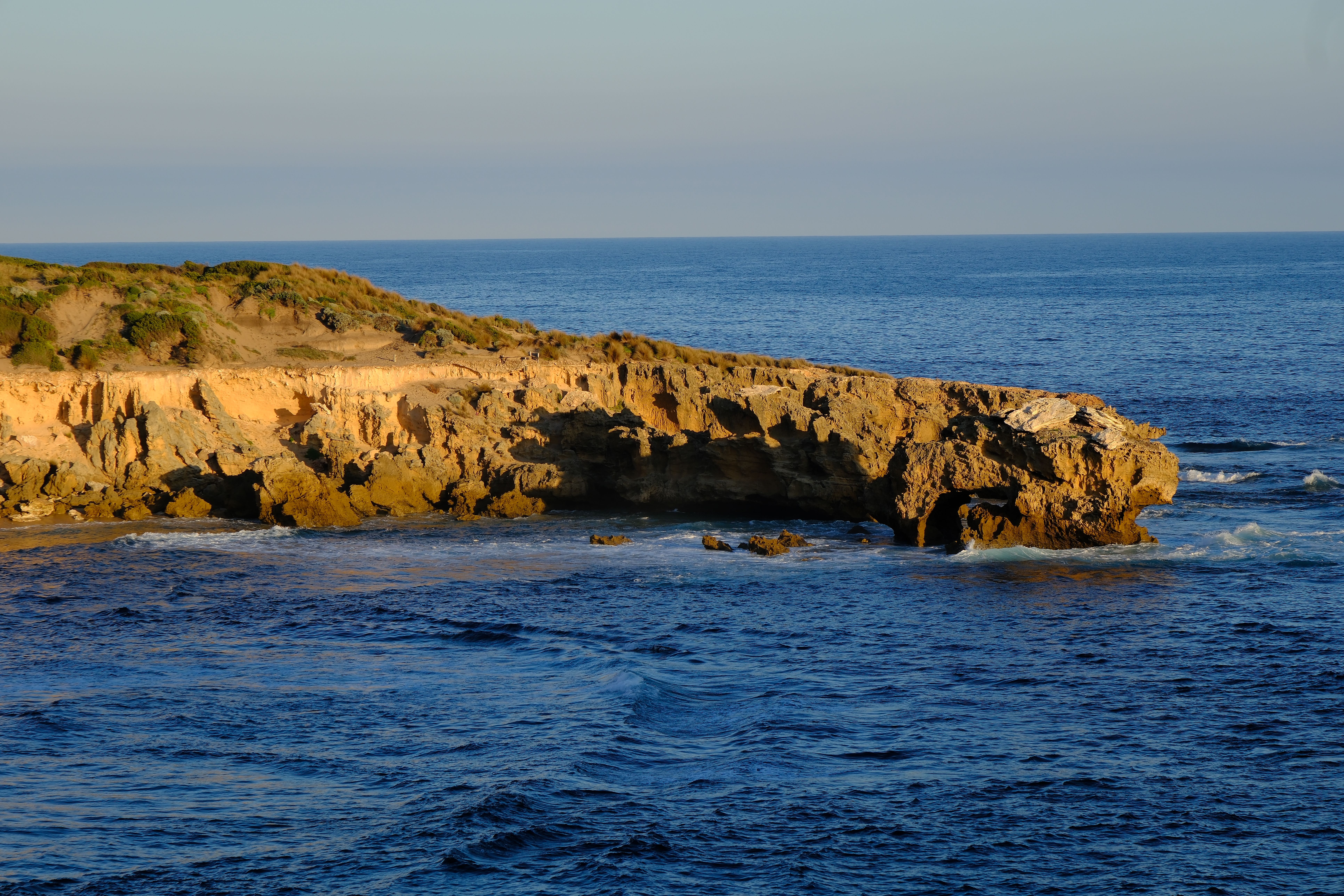 A beautiful coastal cliff reflecting on the ocean at sunset, capturing nature's serenity. - Photo by Walter Coppola on Pexels