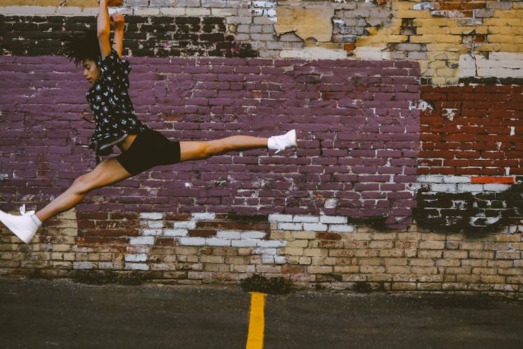 Photo Of Person Jumping Near Brick Walls