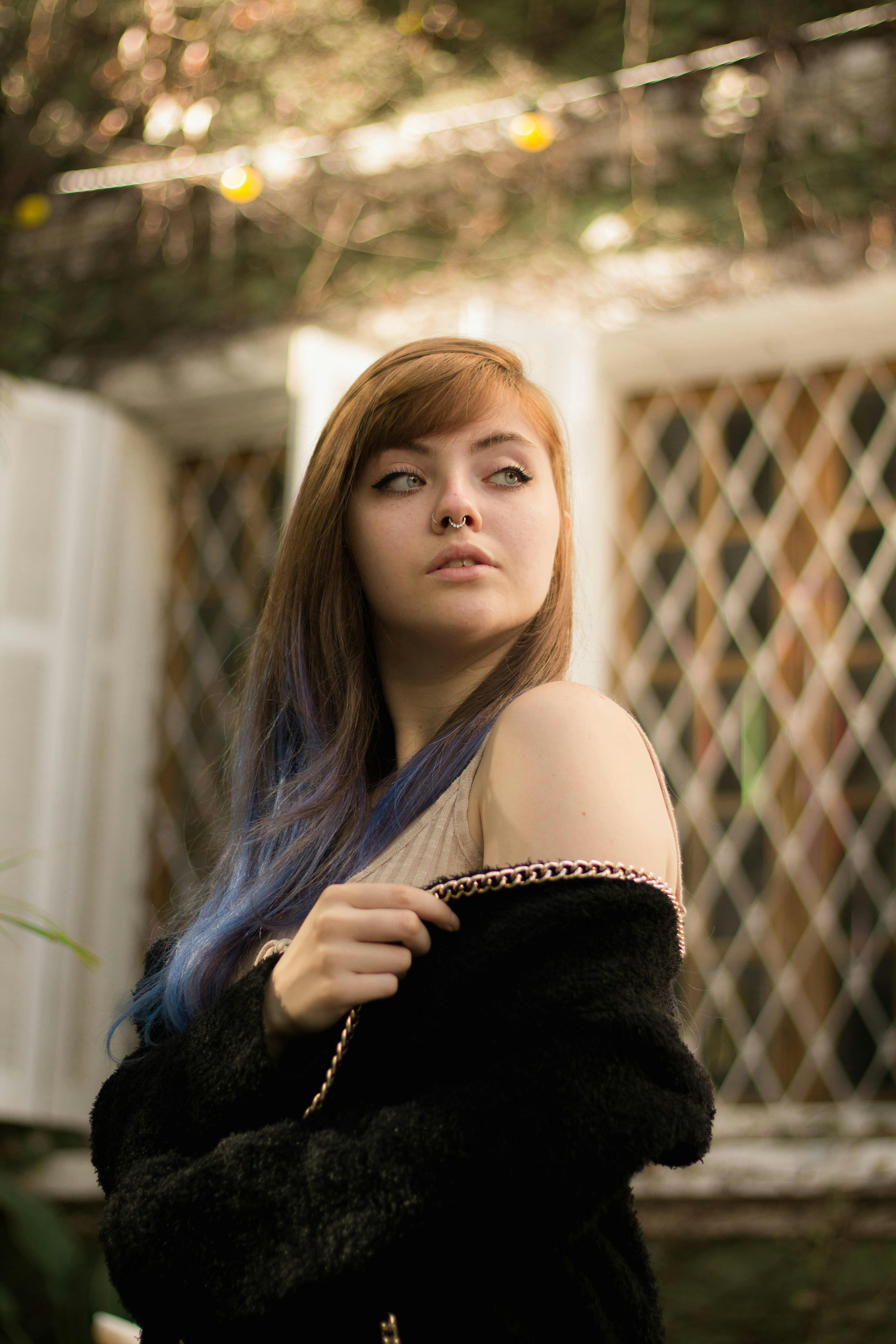 一幅置于户外复古环境中的年轻女子肖像，她有着棕色头发和蓝色亮点