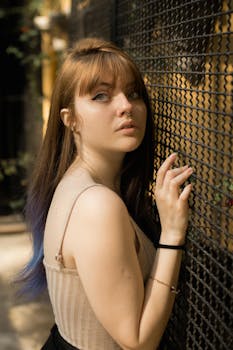 一位年轻女子身着休闲装，倚靠在金属栅栏上的肖像