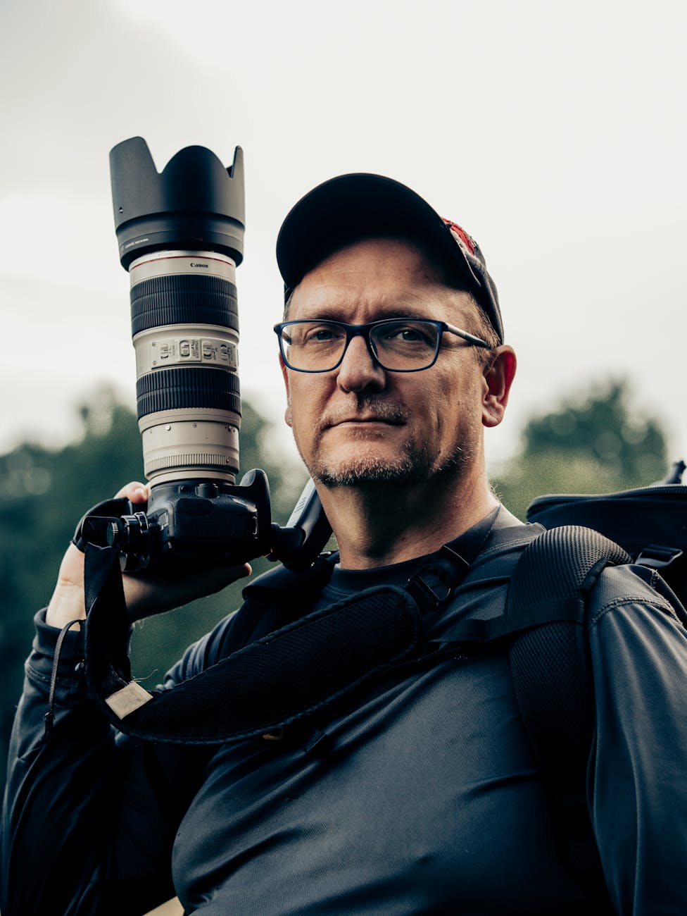 Portrait of a photographer carrying a camera with a telephoto lens outdoors in Atlanta.