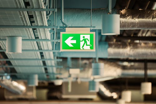 A green exit sign hanging from the ceiling