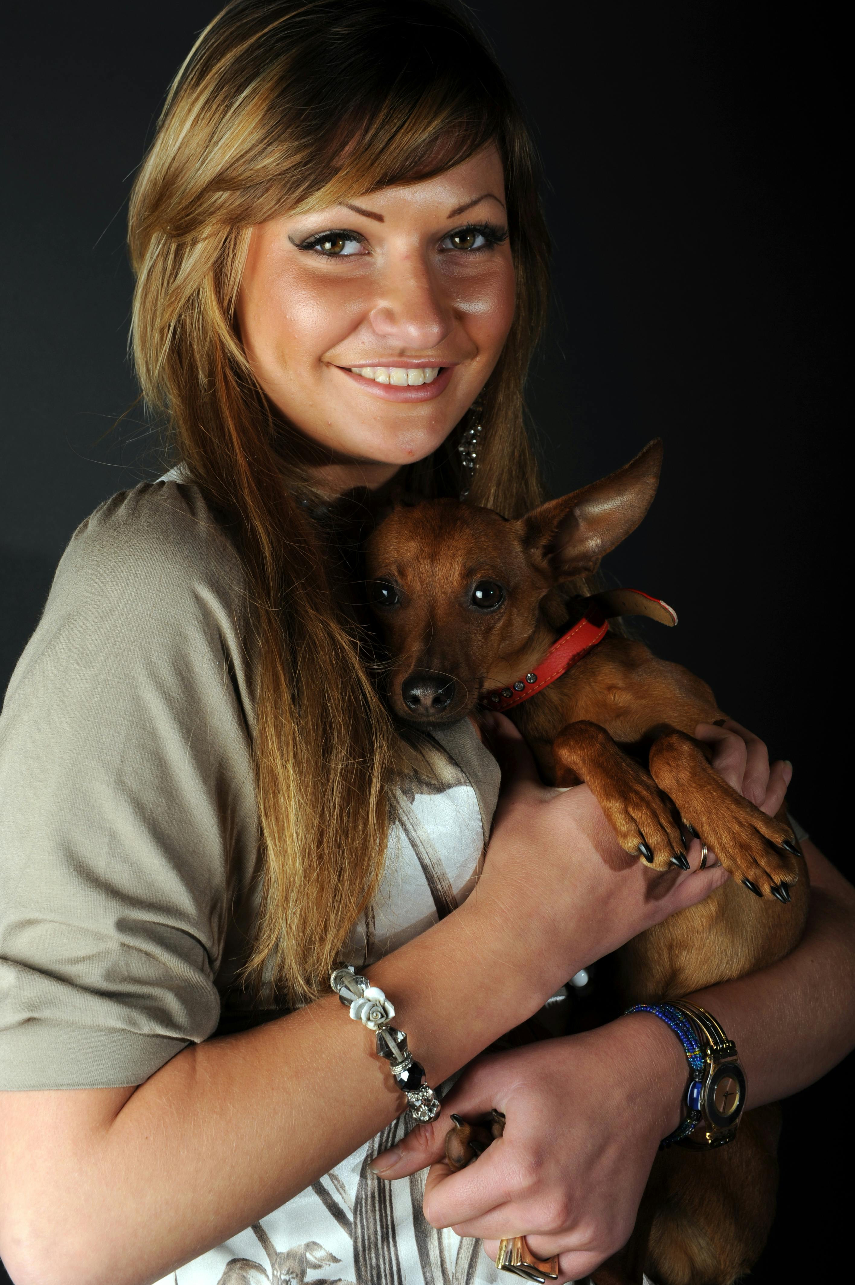 A Woman Hugging a Dog Against Black Background