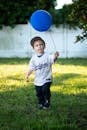 Child in Sportswear Holding Blue Balloon