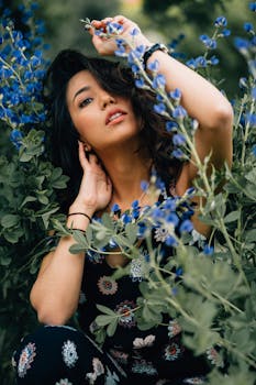 一位身着花卉服装的美丽女子在户外与充满活力的蓝色花朵合影