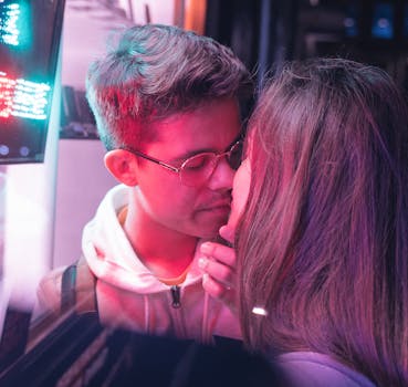 在剑桥，一对年轻夫妇在充满活力的霓虹灯下温柔地接吻