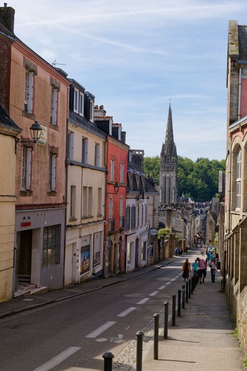 Free Scenic view of a narrow street with colorful buildings and a church tower in France. Stock Photo