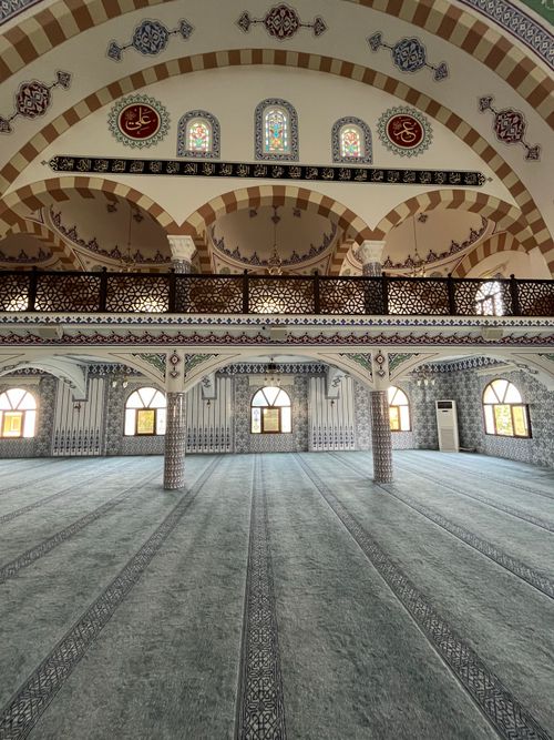 Free Explore the detailed Islamic architecture with arches and spacious design in this mosque interior. Stock Photo