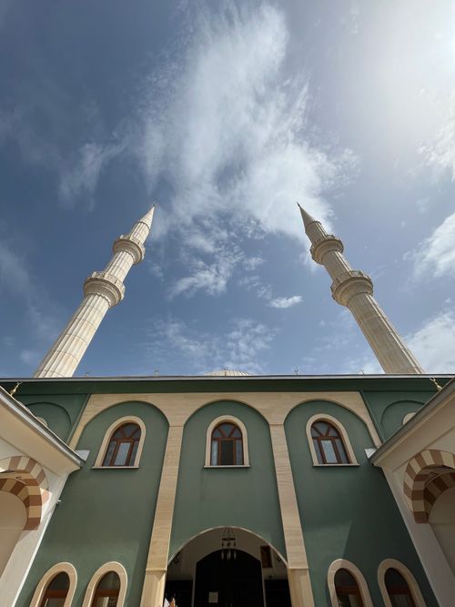 Free Elegant mosque with tall minarets reaching skyward against a backdrop of picturesque clouds. Stock Photo