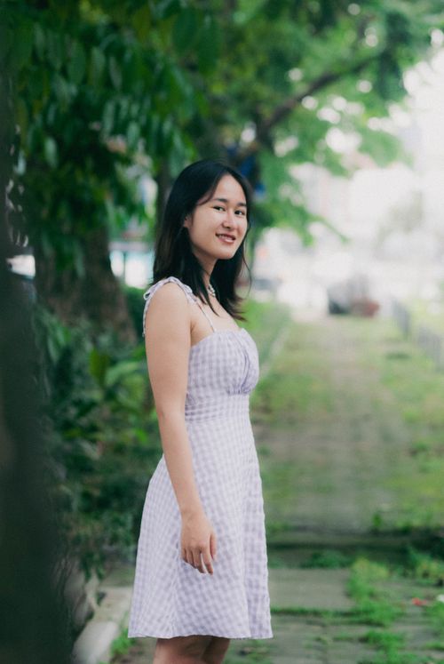 Free Portrait of a smiling young woman in a summer dress posing outdoors in a park setting. Stock Photo