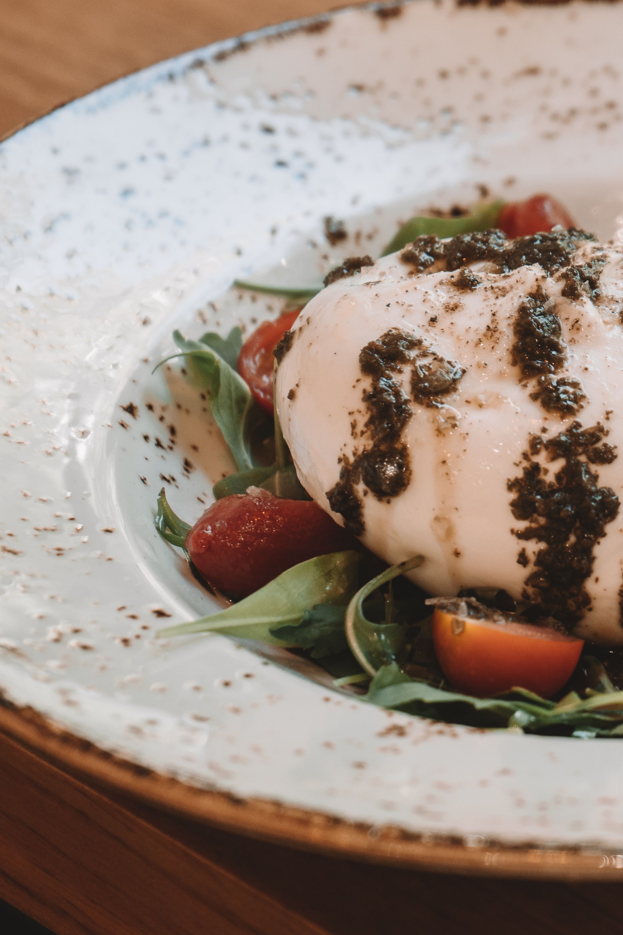 Fotomural Burrata cremosa sobre rúcula y tomates rociados con pesto, un delicioso plato italiano.
