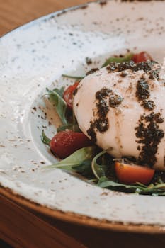 Creamy burrata on arugula and tomatoes drizzled with pesto, a delicious Italian dish.