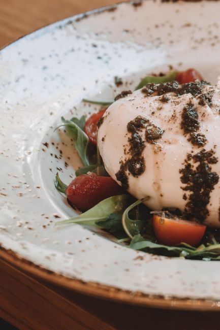 Fotomural Burrata cremosa sobre rúcula y tomates rociados con pesto, un delicioso plato italiano.