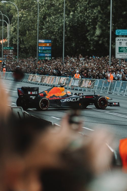 Free Captivating street race featuring a high-speed Formula One vehicle surrounded by cheering crowds. Stock Photo