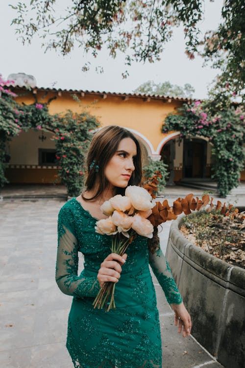 Foto De Mulher Usando Vestido Verde Enquanto Segura Flores