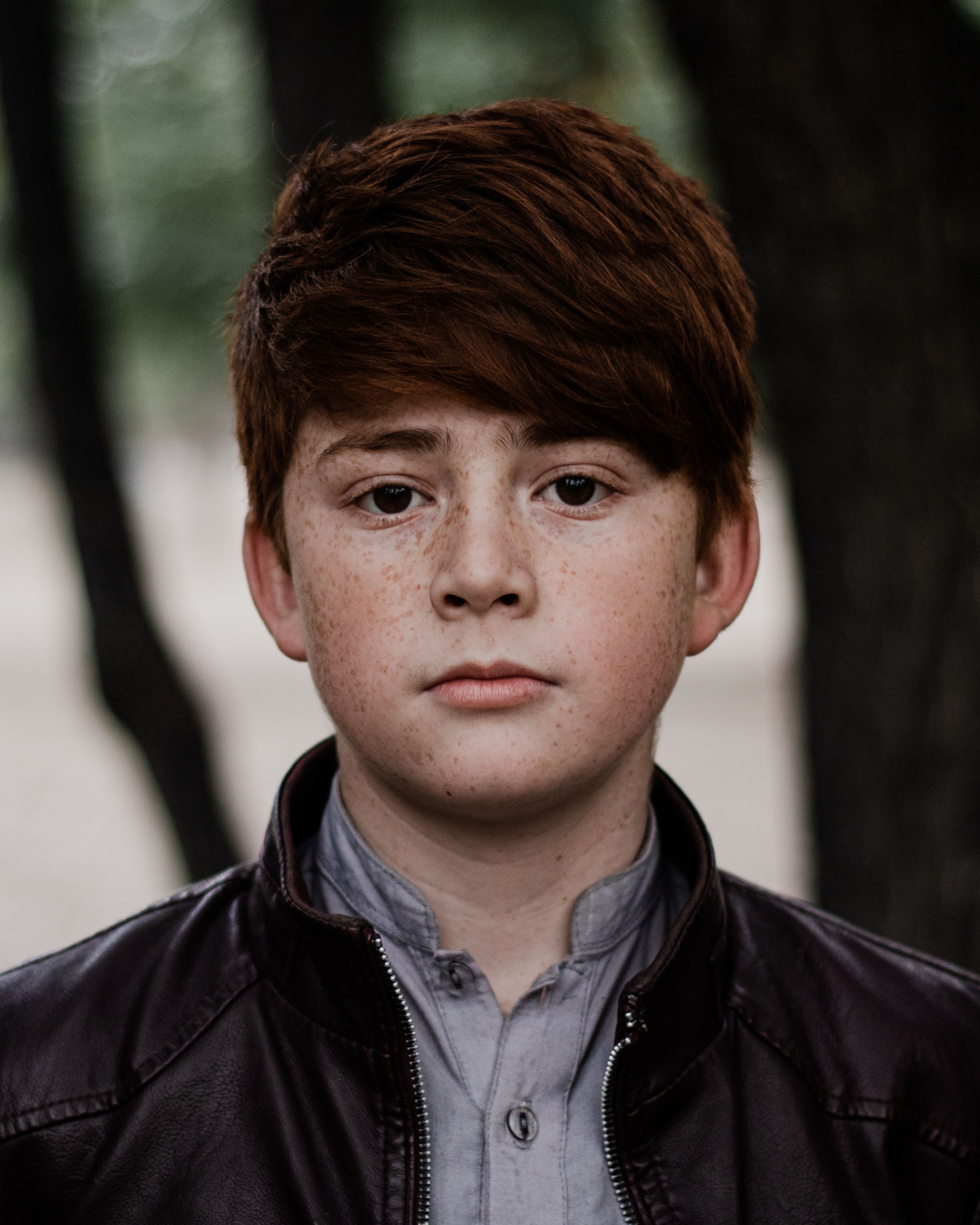 Close-up portrait of a redheaded boy with freckles, wearing a jacket outdoors in Skardu.