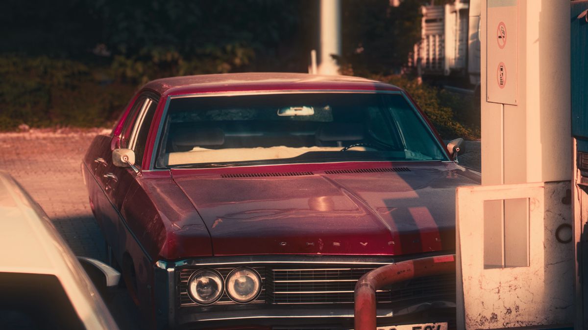 Burgundy vintage car parked at a classic roadside service station