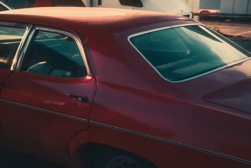 Free Side view of a parked red vintage car, showcasing classic design in warm lighting. Stock Photo