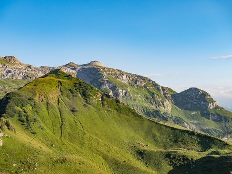Explore a stunning summer mountain landscape in Glarus, Switzerland, showcasing verdant peaks under clear skies.