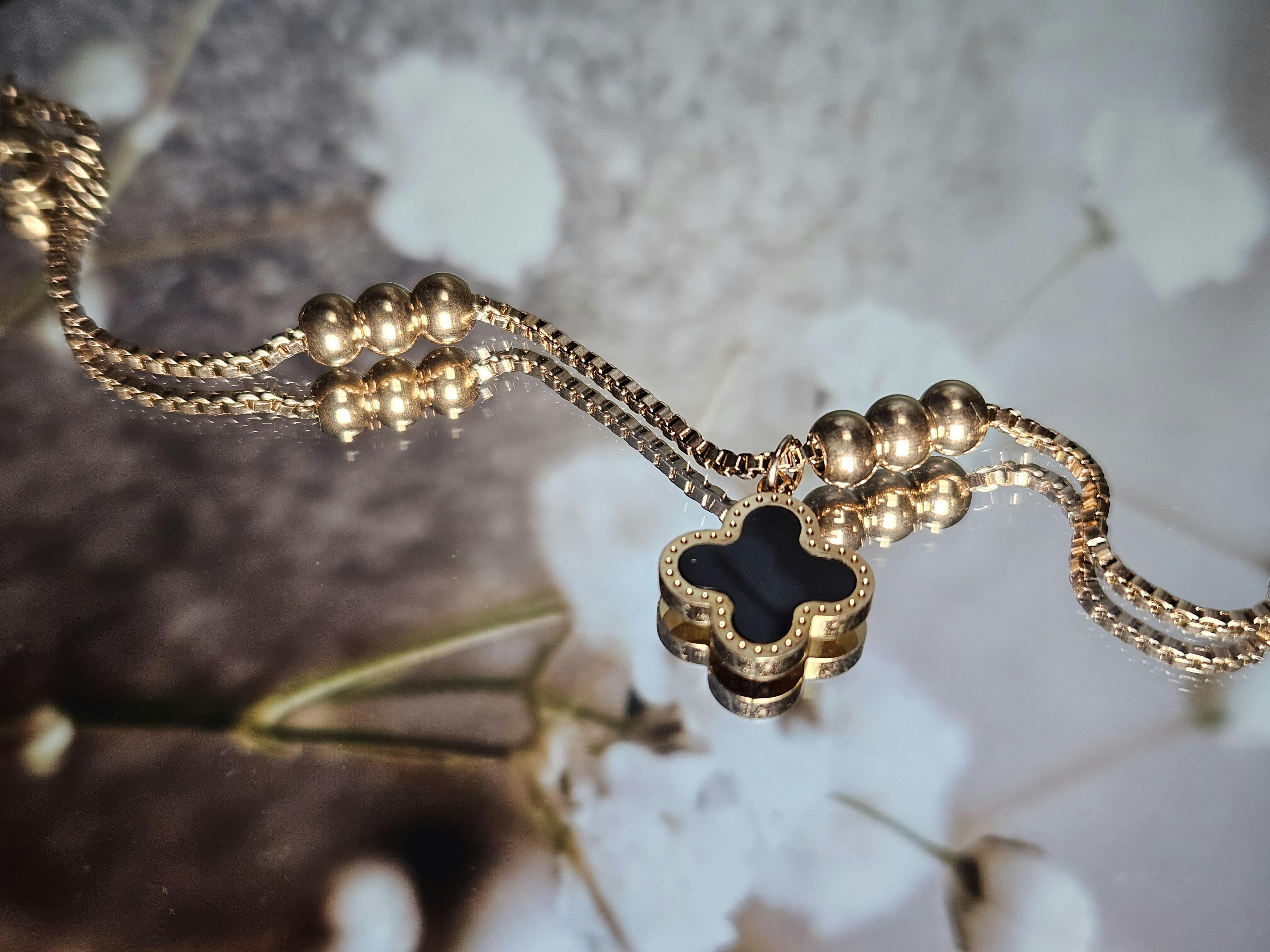 A close-up of a gold PVD-coated necklace and a titanium ring, showcasing their tarnish-free and durable material science.