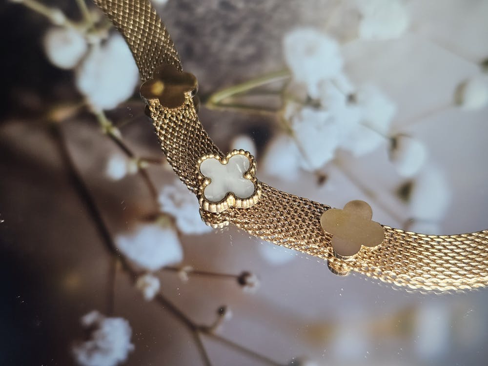 A gold bracelet with white flowers on it