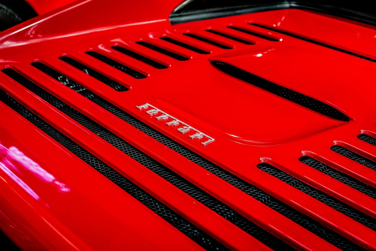 detailed shot of a ferrari emblem on a classic red sports car showcasi