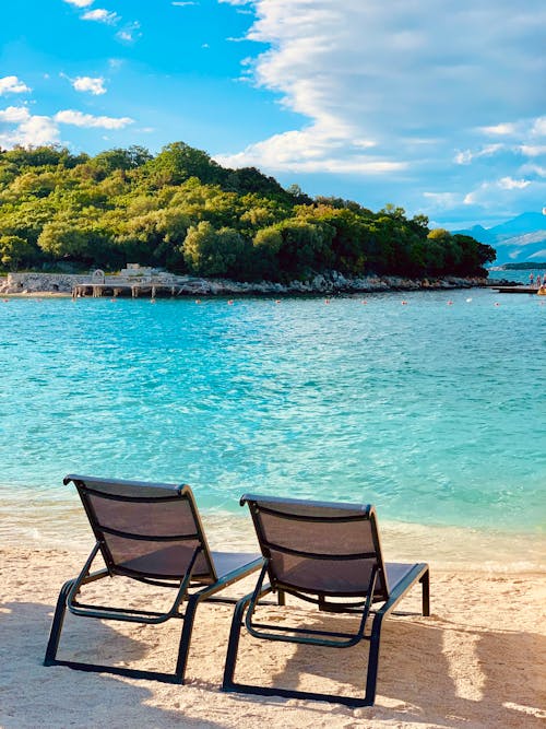Two lounge chairs on the beach with a view of the water