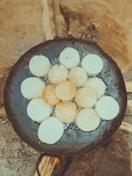 Close-up of traditional Burundian street food cooking on a charcoal stove in an outdoor setting.