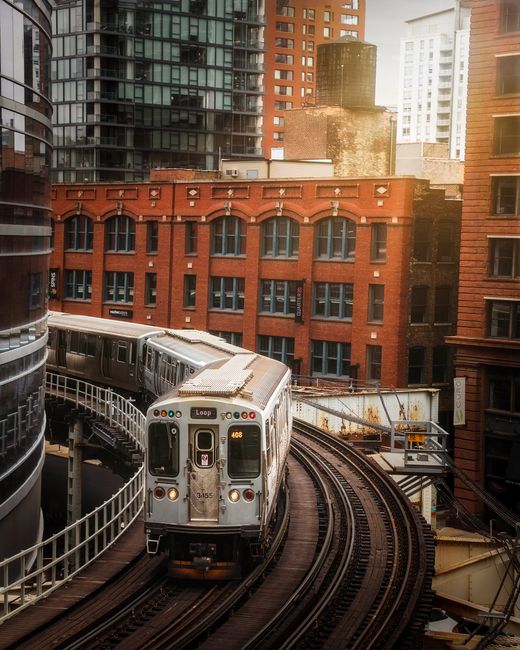 A train navigates through urban city skyscrapers, showcasing modern transportation and architecture.