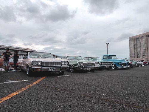 Free Vintage cars in a parking lot under a cloudy sky, showcasing a classic car meetup. Stock Photo