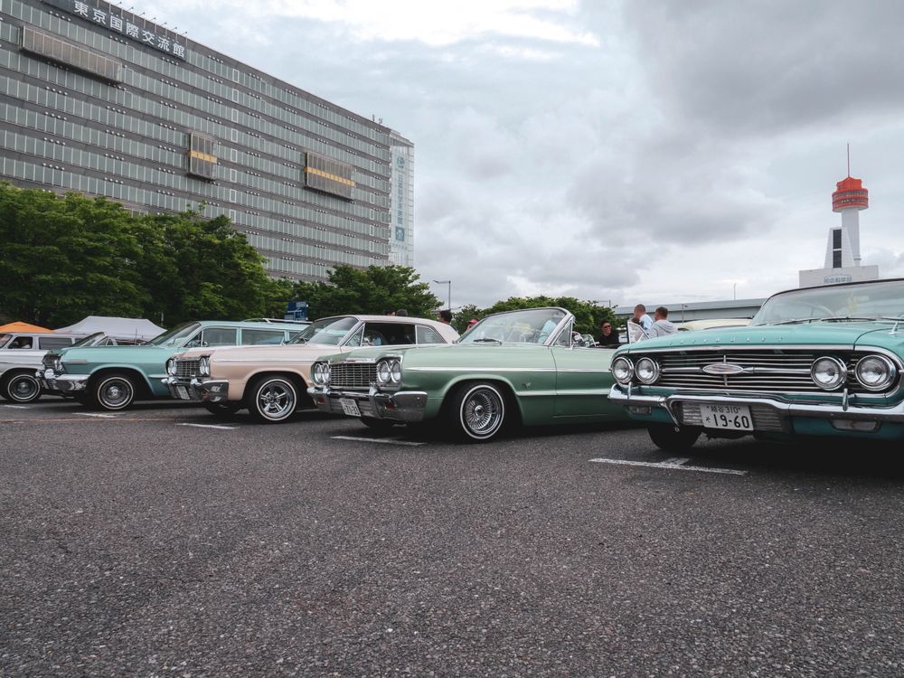 Free A lineup of vintage cars showcased at an outdoor classic car meetup in a city parking lot. Stock Photo