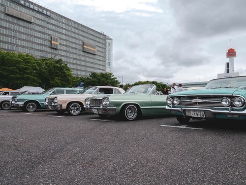 Free A lineup of vintage cars showcased at an outdoor classic car meetup in a city parking lot. Stock Photo