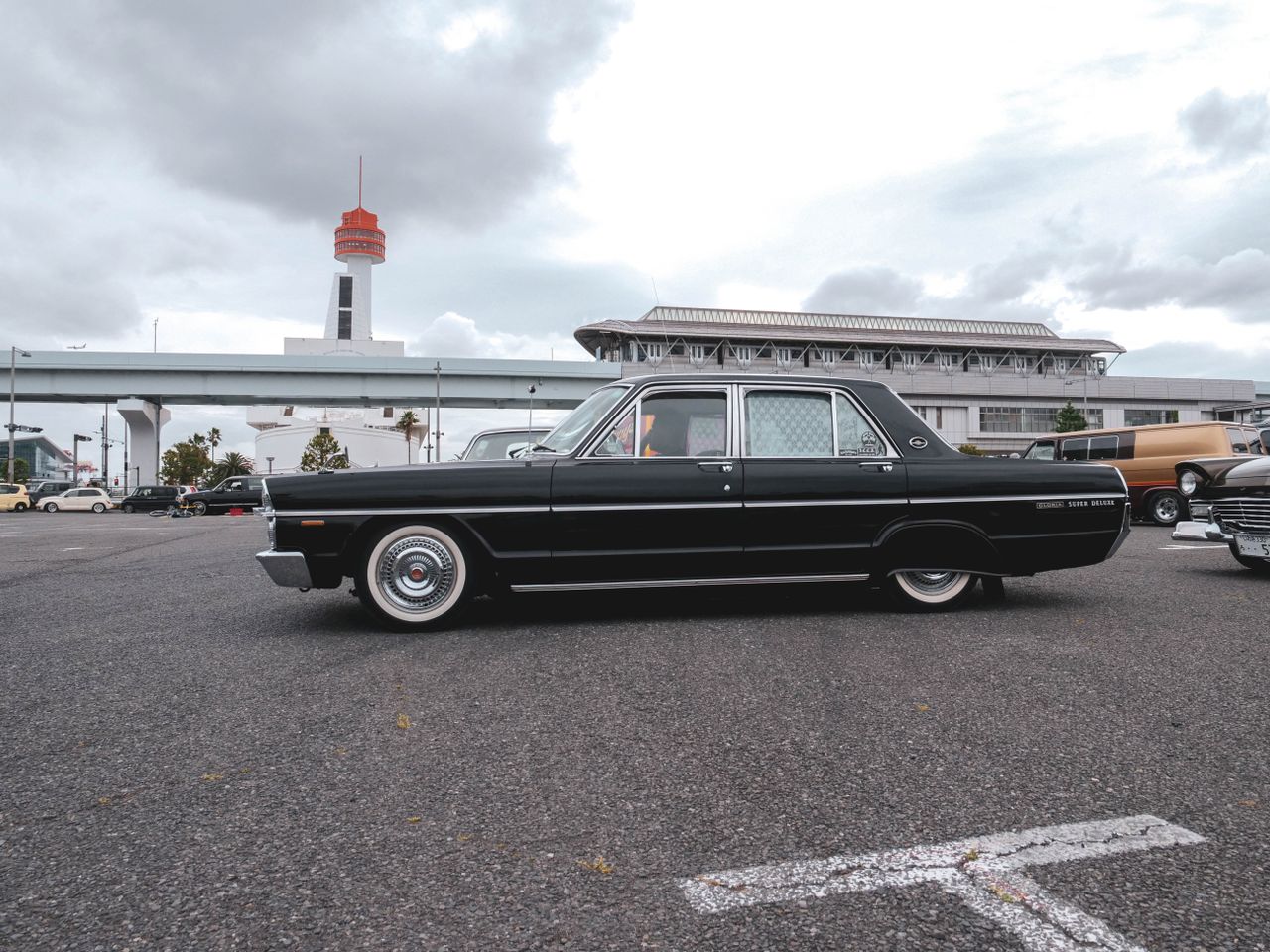 vintage black car parked outdoors with a tower in the background under