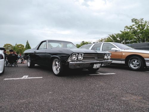 Free Vintage black muscle car showcased at an outdoor car meetup under cloudy skies. Stock Photo